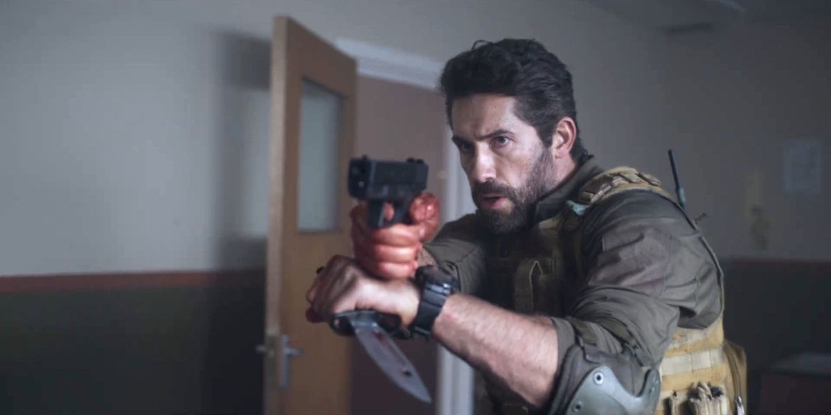 Scott Adkins nei panni di Jake Harris con in mano una pistola e un coltello in One Shot.