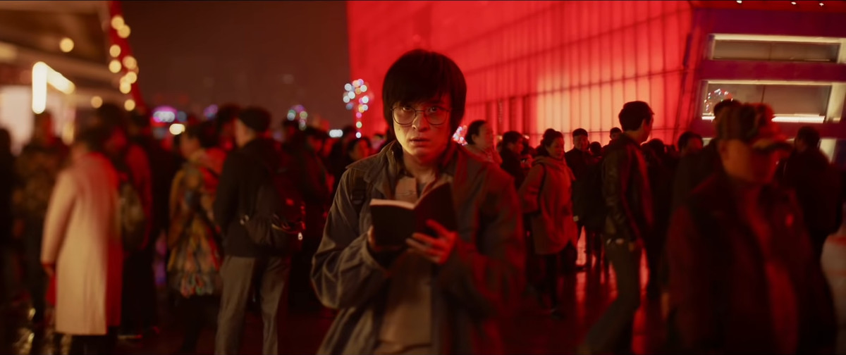 Il personaggio principale di A Writer's Odyssey annota su un taccuino in mezzo alla folla.