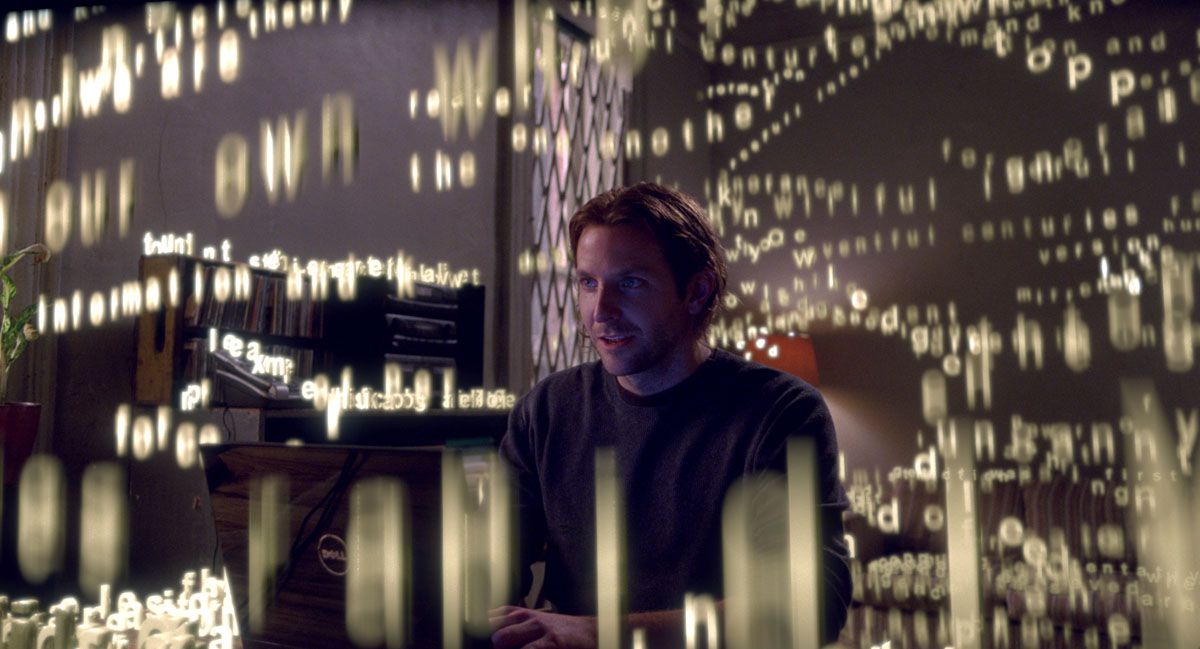 Eddie (Bradley Cooper) digita su un computer mentre le lettere gialle cadono intorno a lui in Limitless.
