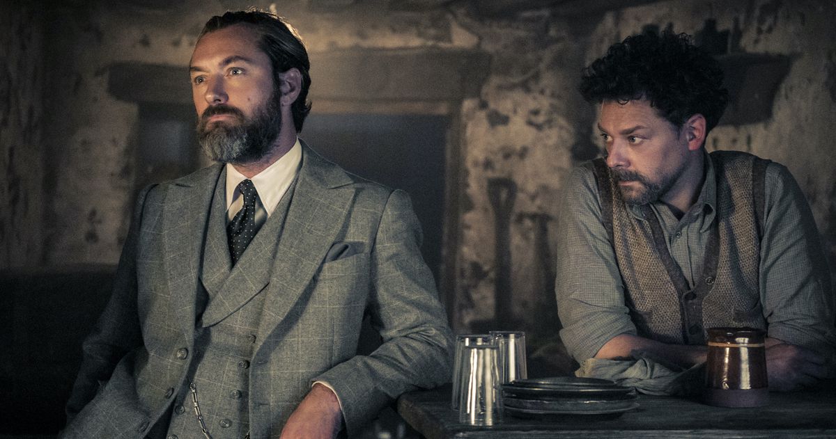 Albus Silente (Jude Law) si appoggia a un bar sudicio come se stesse meditando sui suoi segreti in Animali fantastici: I segreti di Silente