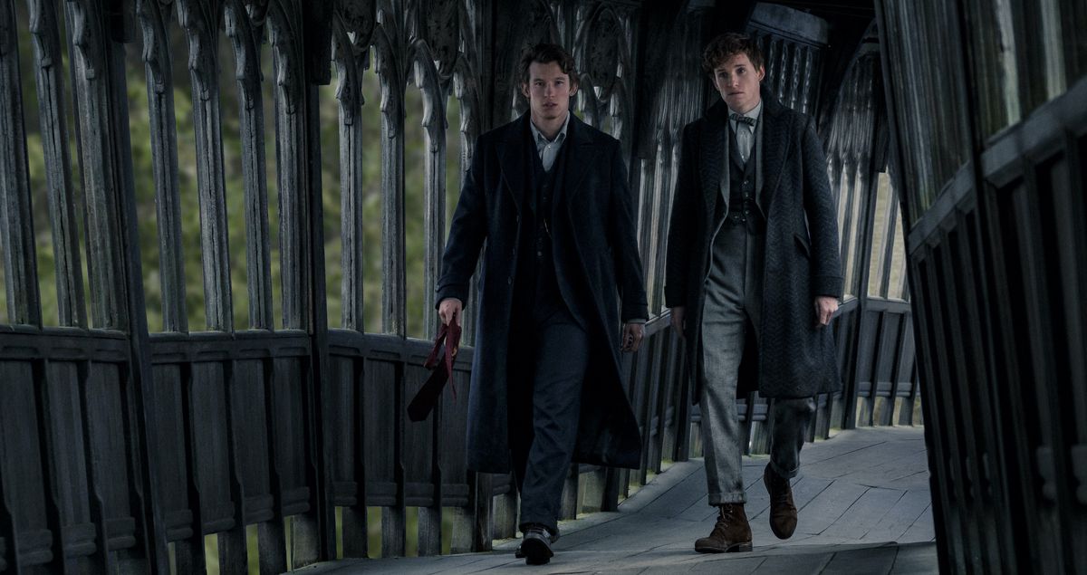 Newt Scamander (Eddie Redmayne) e suo fratello Theseus Scamander (Callum Turner) camminano lungo un corridoio esterno contorto e allacciato in Animali fantastici: I segreti di Silente