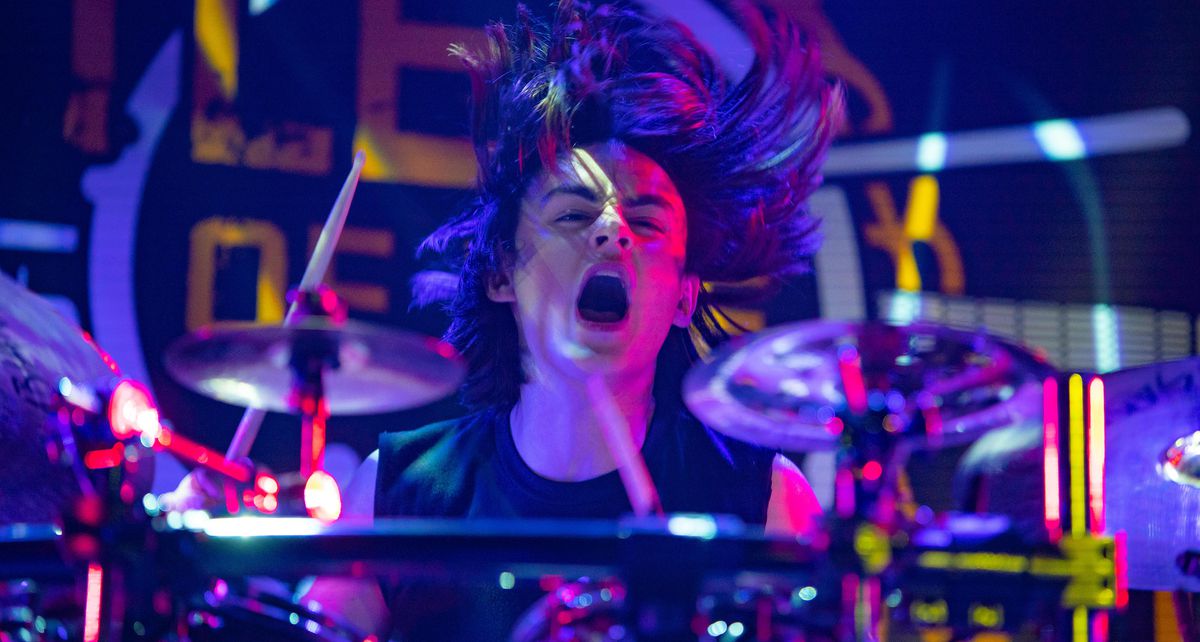 Kevin (Jaeden Martell) balene alla batteria in una scena dai colori neon in Metal Lords