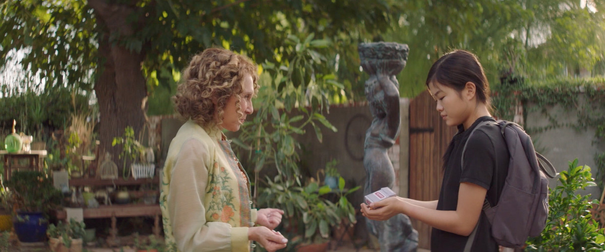 una donna anziana in verde insegna a una ragazza più giovane come fare un trucco magico