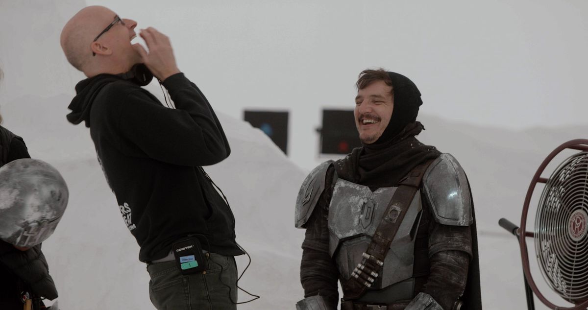 Peyton Reed e Pedro Pascal ridono sul set della seconda stagione di The Mandalorian. Pascal indossa il suo costume, ma senza l'elmo, un cappuccio nero che gli copre la testa e gli scompiglia i capelli.