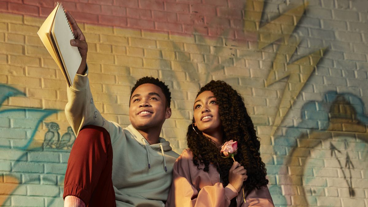 El (Chosen Jacobs) indica con un taccuino a spirale mentre Kira King (Lexi Underwood) osserva in Sneakerella.