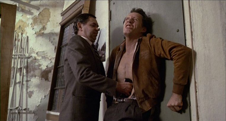 Un altro uomo estrae una videocassetta dalla fessura dello stomaco di James Woods in Videodrome