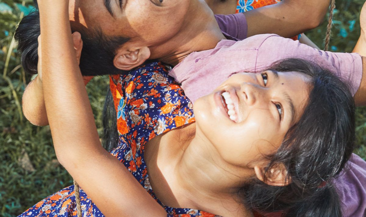 Una ragazza sorride mentre è sdraiata sull'erba a Bulbul Can Sing.