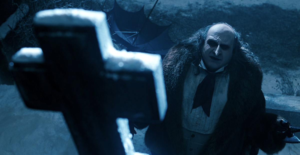 Il pinguino (Danny DeVito) si inginocchia davanti alla tomba condivisa dei suoi genitori in Batman Il ritorno