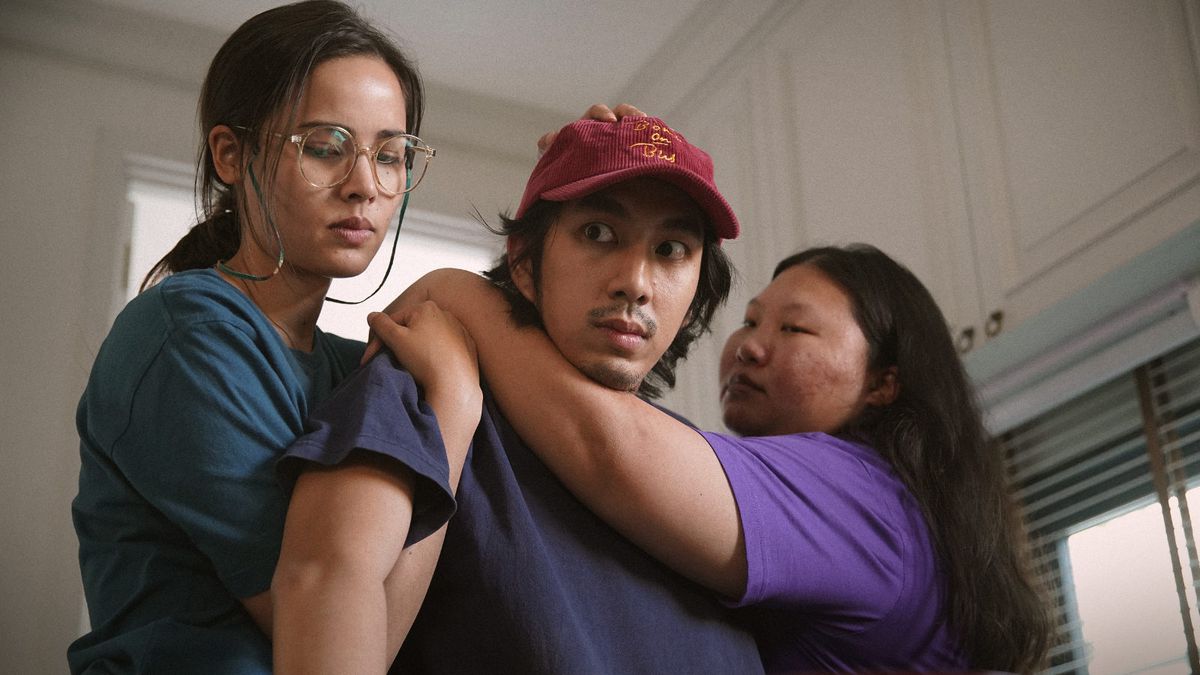 Un uomo con un berretto è trattenuto da due donne in Fast & Feel Love.