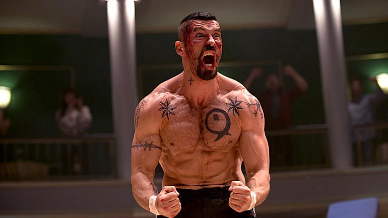 Scott Adkins, volto insanguinato e con il busto pieno di tatuaggi, festeggia dopo un combattimento in Boyka: Undisputed.