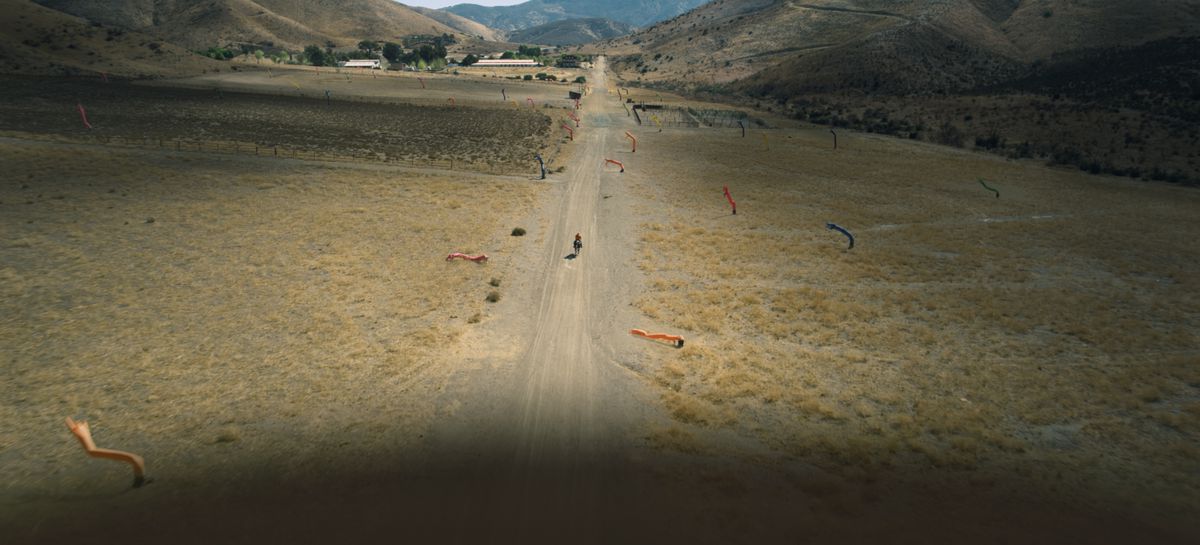 un'ampia ripresa dall'alto di un uomo a cavallo lungo una strada nel deserto a Nope