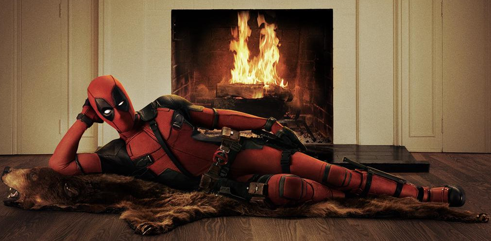 Deadpool di Ryan Reynolds è adagiato in modo civettuolo su un tappeto da orso davanti a un fuoco scoppiettante.