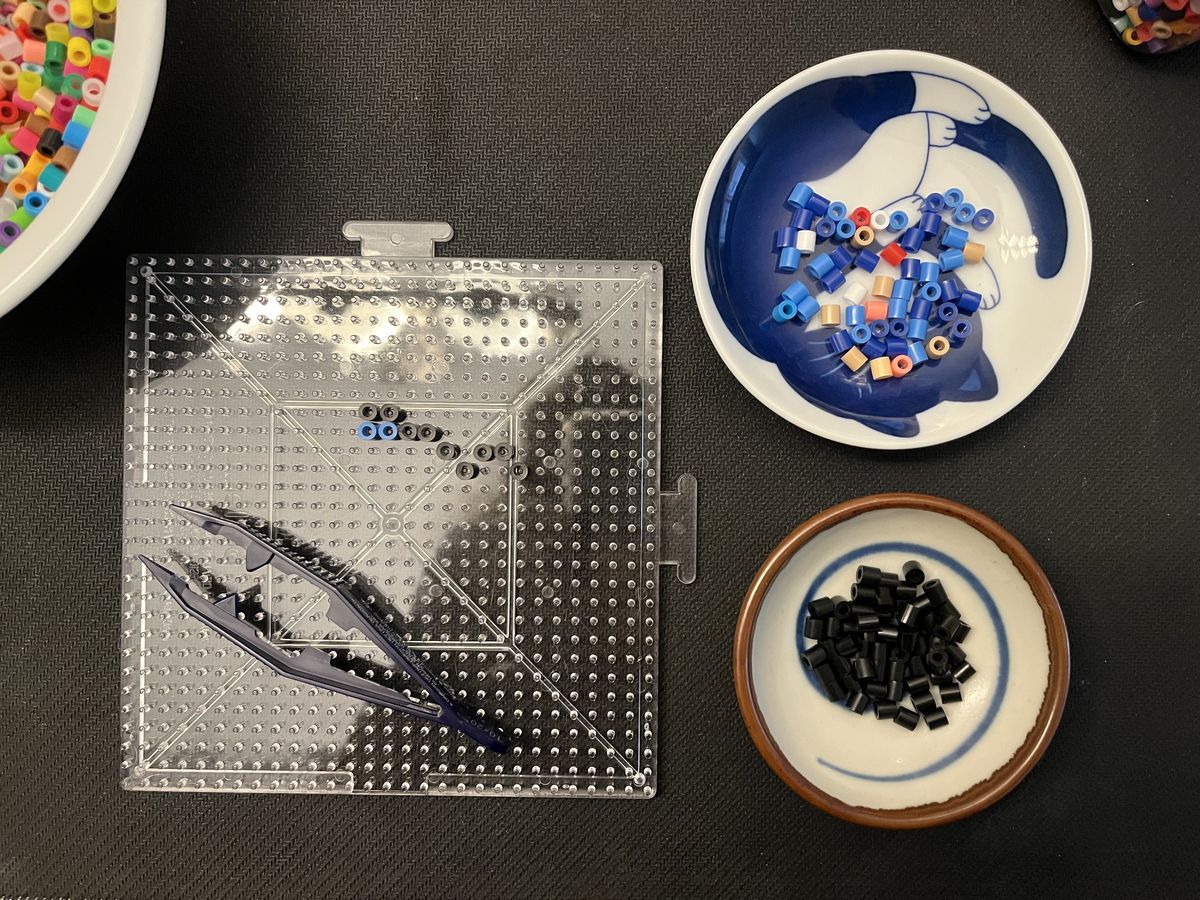 una foto dall'alto in basso di una perlina perline smistata in due ciotole da immersione. ci sono perline nere su uno e perline blu, rosse e albicocca in un altro.