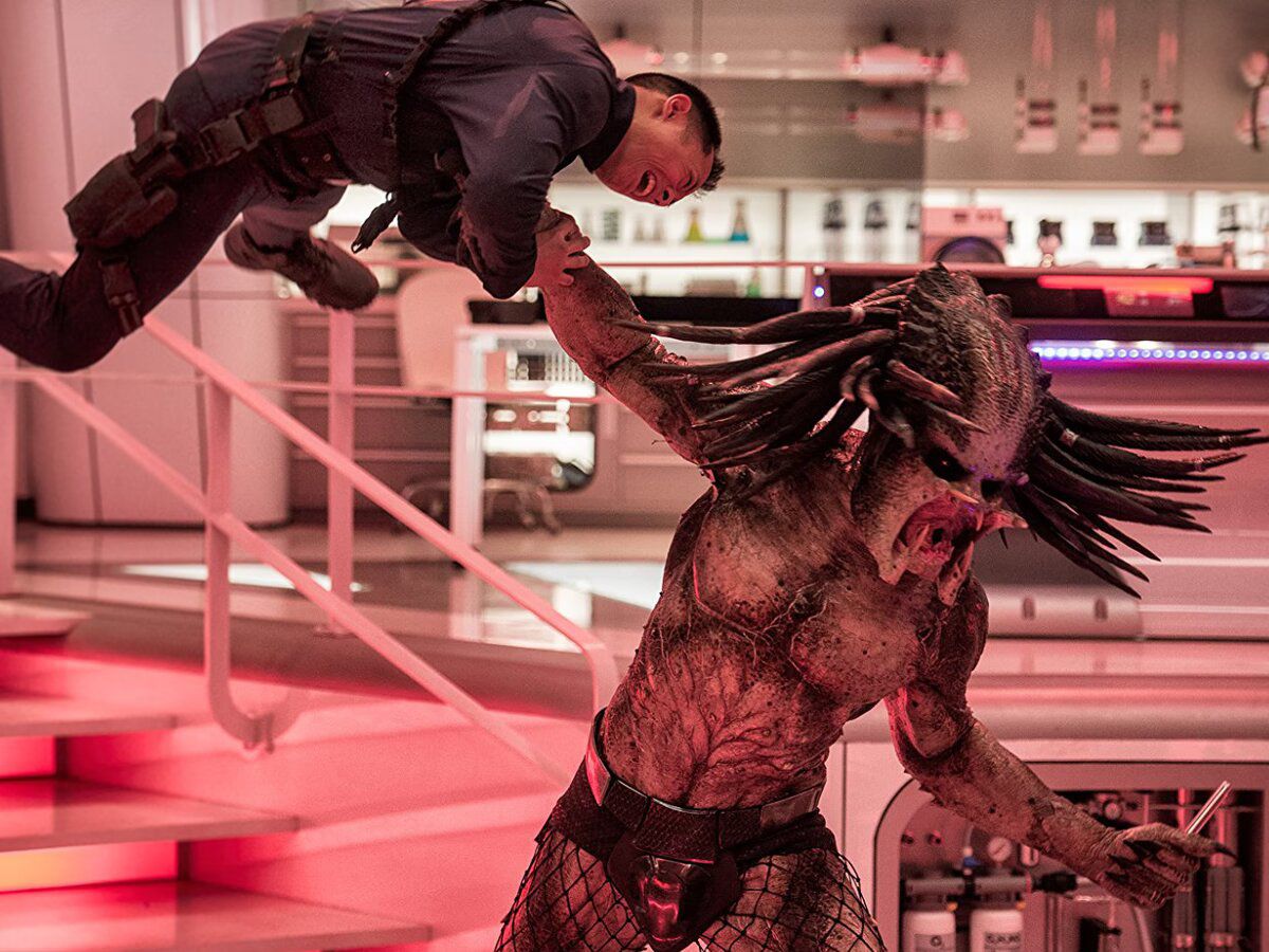 Un Predator senza armatura che solleva in aria una guardia di sicurezza terrorizzata in The Predator.