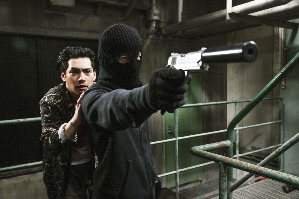 Un uomo mascherato tiene una pistola silenziata con un altro uomo che si nasconde dietro di lui in The Fable.