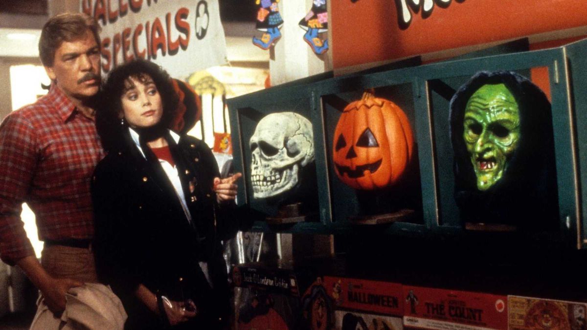 Tom Atkins nei panni del dottor Dan Challis e Stacey Nelkin nei panni di Ellie Grimbridge guardano una mostra di maschere di Halloween in Halloween III: La stagione della strega.