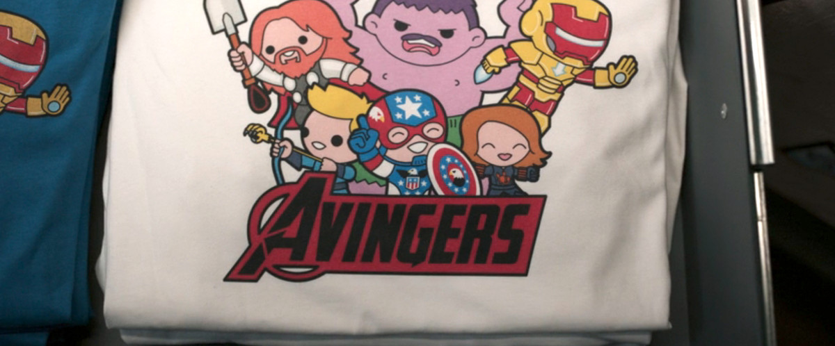 una t-shirt bianca con i disegni chibi dei personaggi degli avengers, ma tutti leggermente spenti.  la carcassa è viola, thor ha i capelli rossi, e sotto c'è scritto Avingers