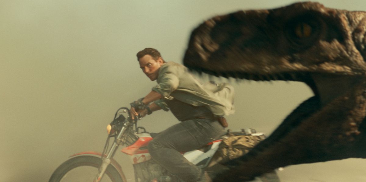 Owen Grady (Chris Pratt) storce gli occhi in modo comico mentre tenta di sfuggire a un dinosauro inseguitore mentre guida una motocicletta in una foto pubblicitaria ufficiale di Jurassic World Dominion. No, questo non è uno screengrab che abbiamo realizzato, anche se sembra stranamente sfocato e un po' Photoshoppato.