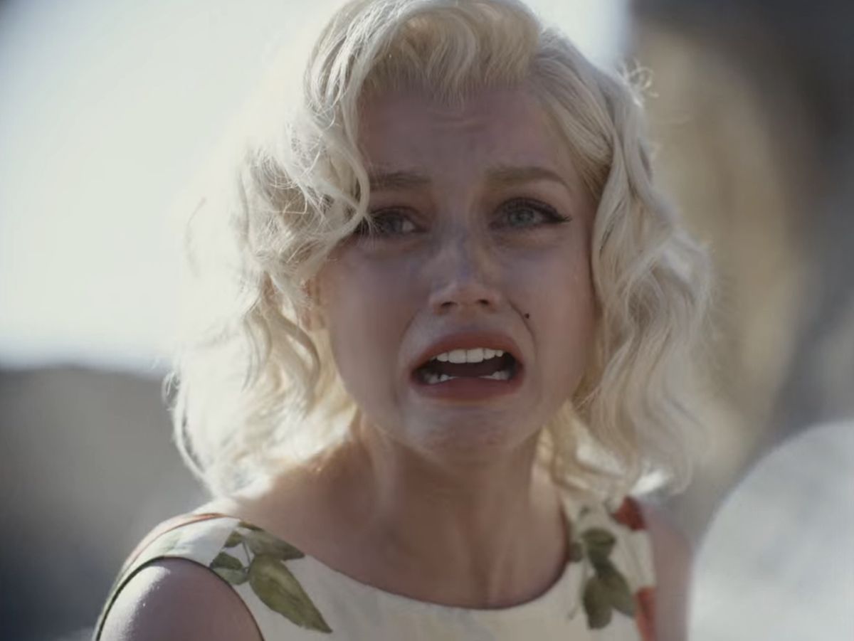 Ana de Armas nei panni di Marilyn Monroe in Blonde, che indossa un vestito a fiori sulla spiaggia e singhiozza