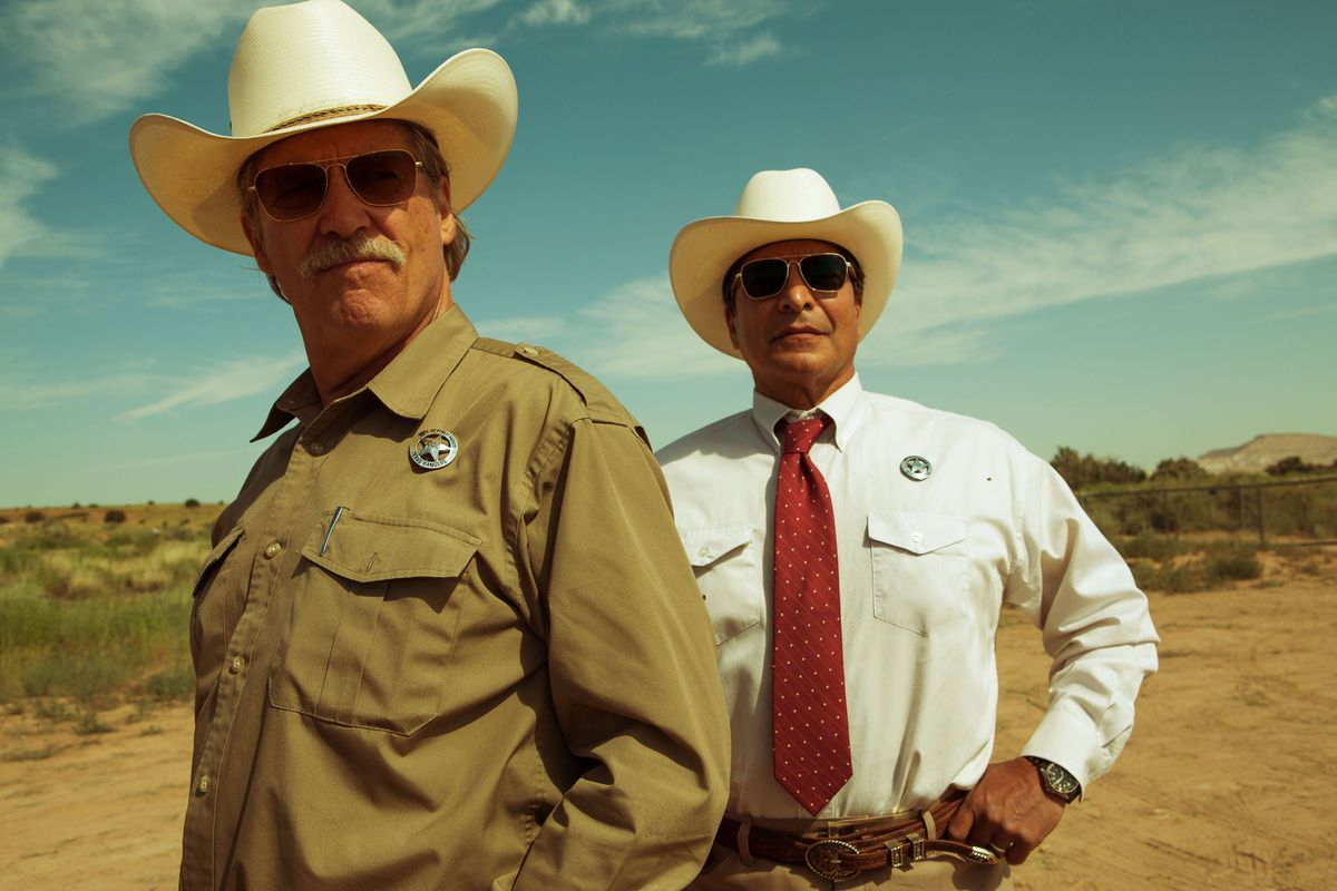 Jeff Bridges e Gil Birmingham in Hell or High Water. Entrambi indossano abiti dei Texas Rangers, con cappelli da cowboy e occhiali da sole.