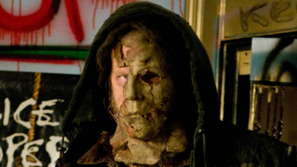 La faccia barbuta di Tyler Mane fa capolino da dietro una maschera a brandelli di Michael Myers in Halloween II.