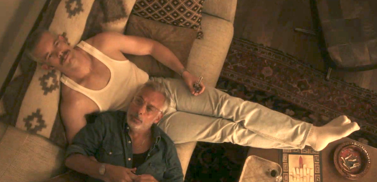 due uomini si siedono su un divano, sdraiati l'uno nelle braccia dell'altro