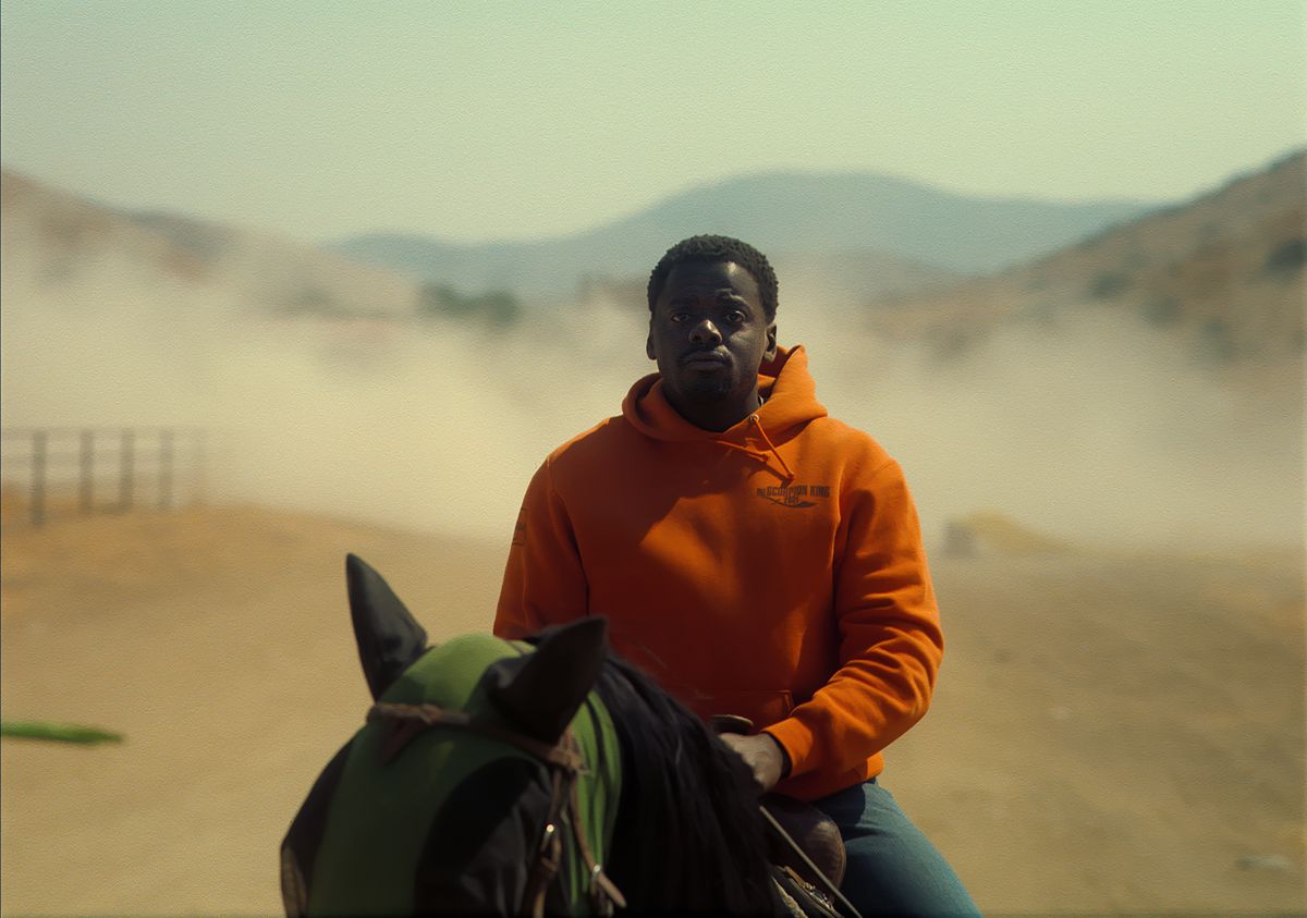 OJ (Daniel Kaluuya), che indossa una felpa con cappuccio arancione di The Scorpion King, cavalca un cavallo verso la telecamera in Nope