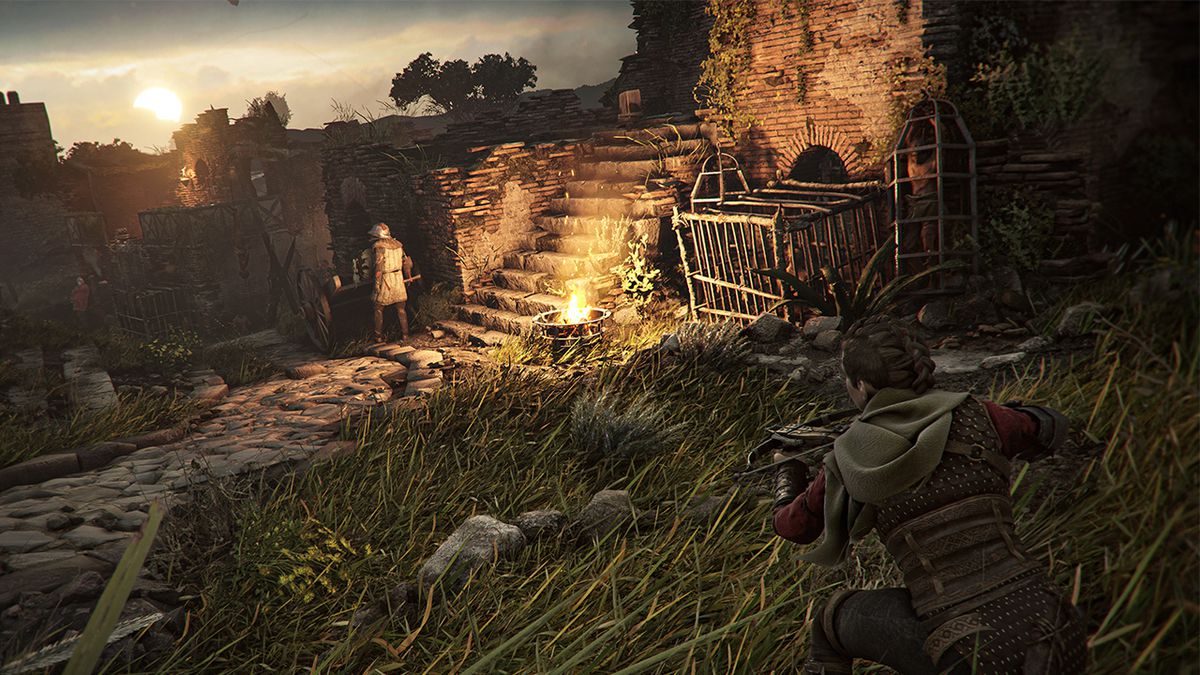 Amicia si intrufola nell'erba alta e punta la sua balestra verso un nemico vicino durante il tramonto in A Plague Tale: Requiem