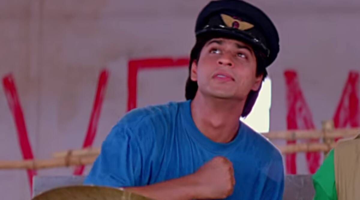 Shah Rukh Khan tiene il pugno sul petto mentre indossa una camicia blu e un cappello da pilota in Kabhi Haan Kabhi Naa.