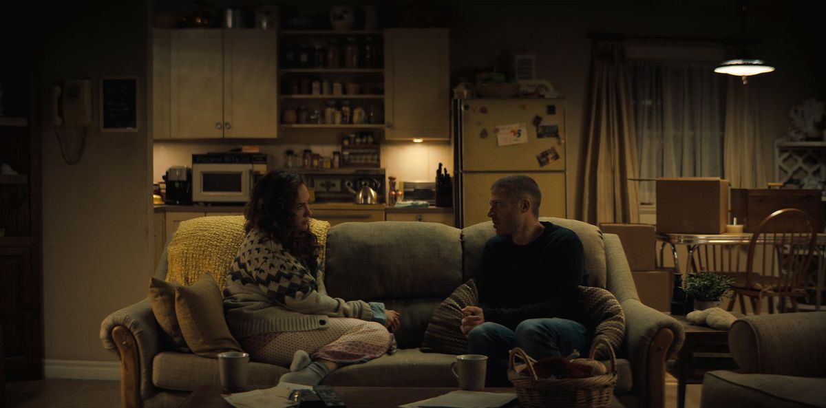 Erin e Riley sedute sul divano per metà l'una di fronte all'altra; puoi vedere la sua cucina e la sala da pranzo sullo sfondo