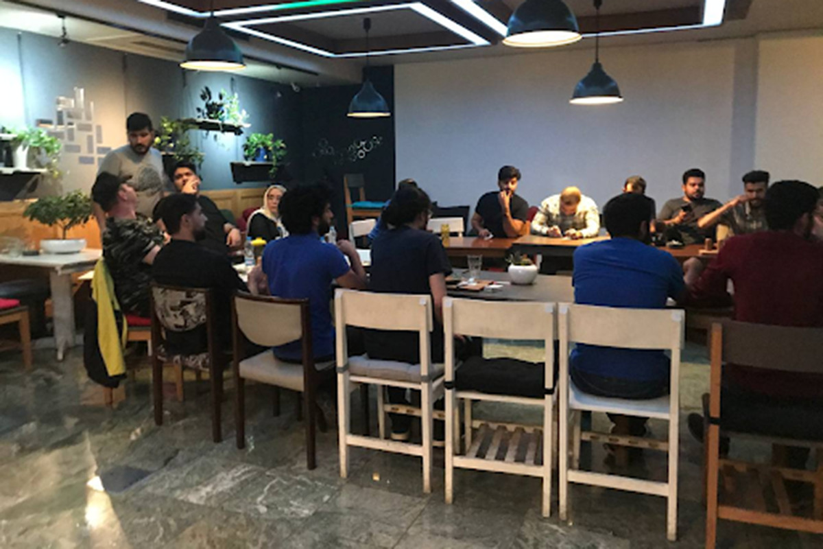 Un'enorme disposizione di tavoli a forma di U per più di una dozzina di giocatori in un grande gioco sociale al Dressage Cafe.