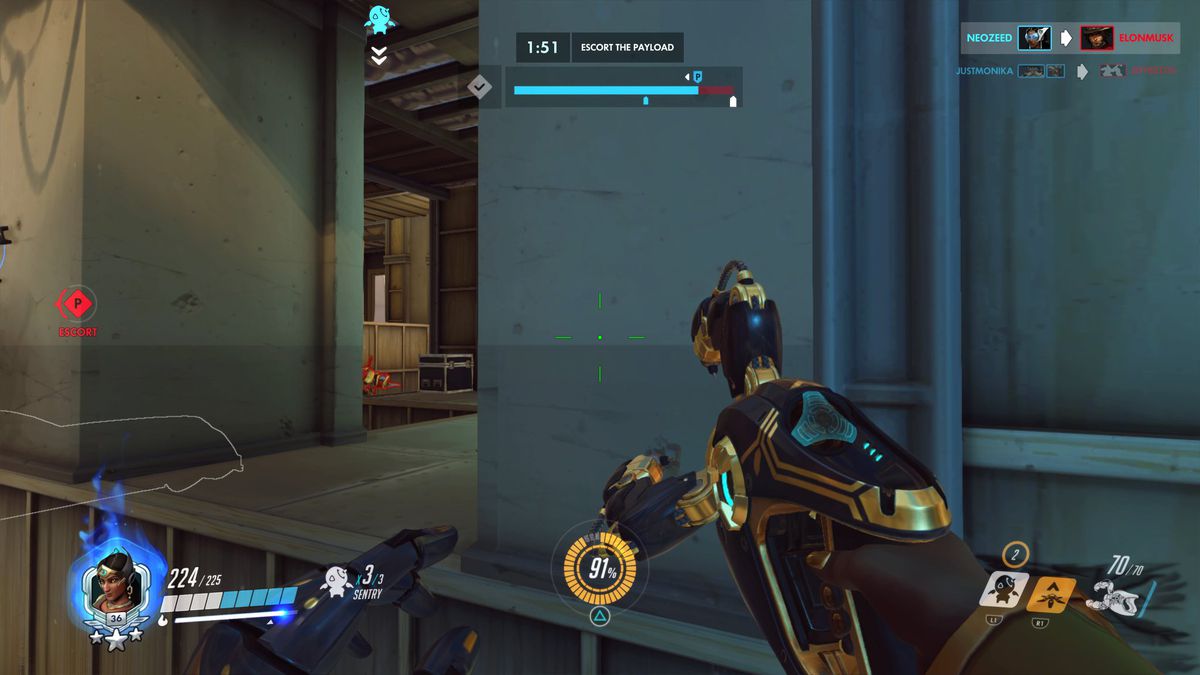 Una visione in prima persona dell'Overwatch originale come Symmetra. Il giocatore si sta muovendo verso il carico utile sulla mappa ibrida Hollywood e l'interfaccia utente del personaggio del giocatore indica che è