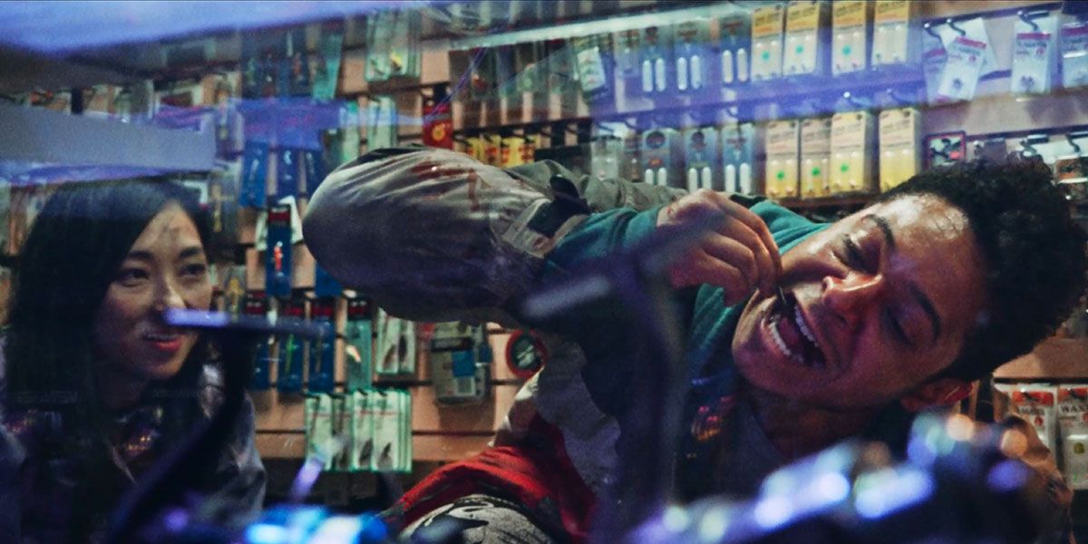 Un giovane (Phillip Andre Botello) si appoggia al bancone di un negozio e fa penzolare un verme nero nella sua bocca aperta, mentre una giovane donna nell'angolo sinistro osserva.