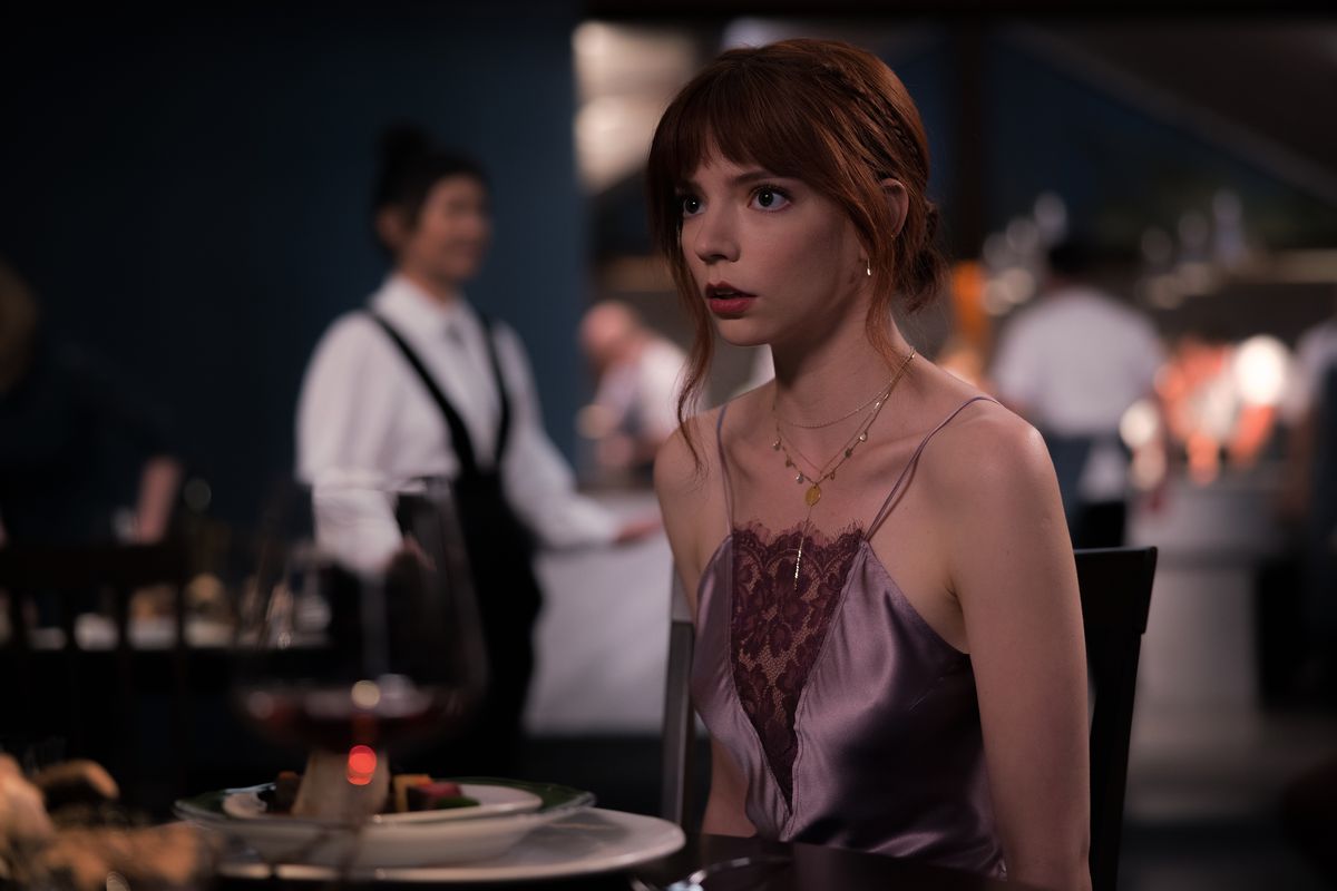 Margo (Anya Taylor-Joy), una giovane donna con un vestito trasparente con spalline sottili, fissa qualcosa fuori campo con un'espressione inorridita in The Menu