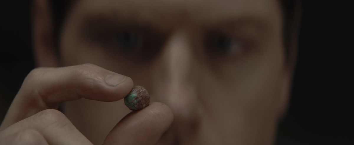 Il burocrate teso Syril Karn (Kyle Soller) osserva con aria minacciosa un singolo soffio di cereali stretto tra il suo dito e il pollice ad Andor