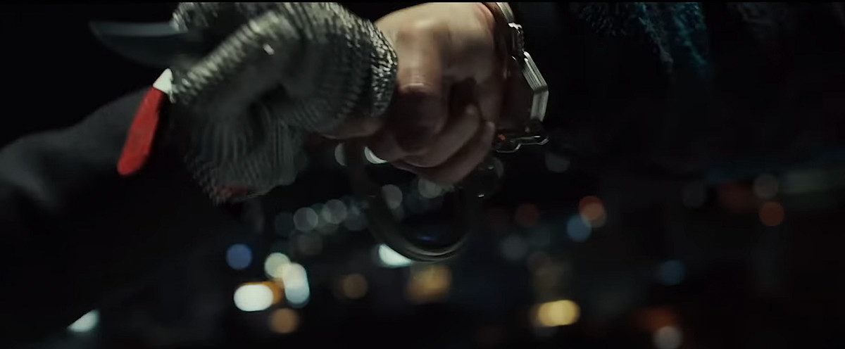 Due mani leggermente sfocate lottano in primo piano in una ripresa di Decision to Leave: una brandisce un coltello, l'altra indossa un guanto di cotta di maglia