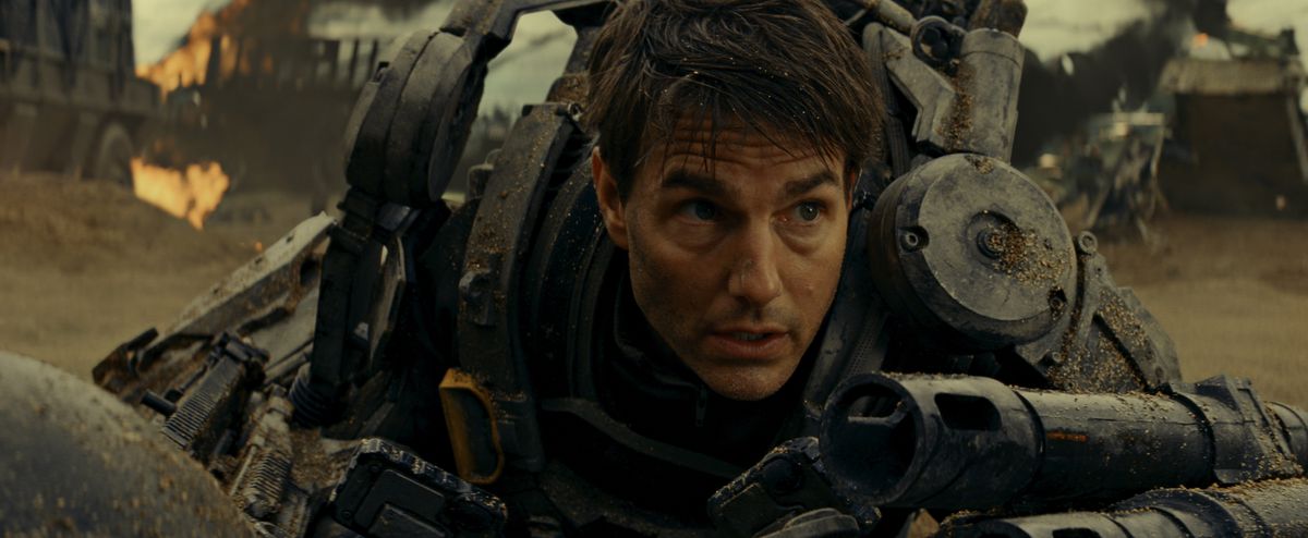 L'ufficiale militare di Tom Cruise in tuta esplosiva cade a terra riprendendo fiato durante la foga della guerra aliena in Edge of Tomorrow