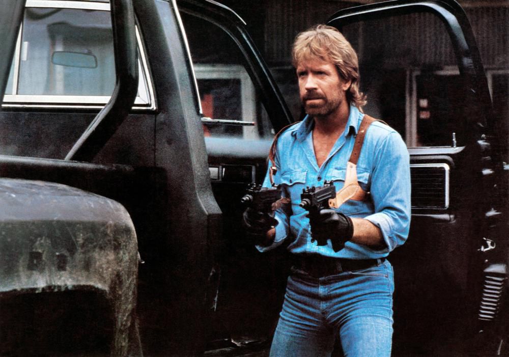 Chuck Norris indossa un sacco di jeans mentre impugna due Uzi in Invasion USA