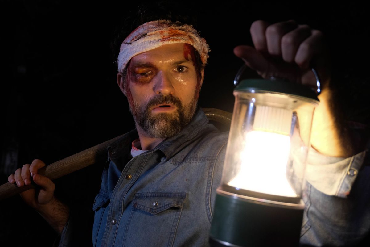 Josh Ruben del film horror Shudder A Wounded Fawn che porta una lanterna con una benda in testa