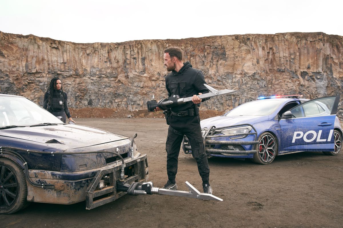 Alban Lenoir è vestito di nero e appone dei bastoncini sulla parte anteriore della sua auto in Lost Bullet.