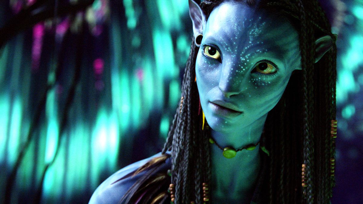 Neytiri, un alieno dalla pelle blu con grandi occhi e capelli strettamente intrecciati, in Avatar.  Ha segni luminosi sul viso e indossa una collana girocollo con un grande ciondolo.