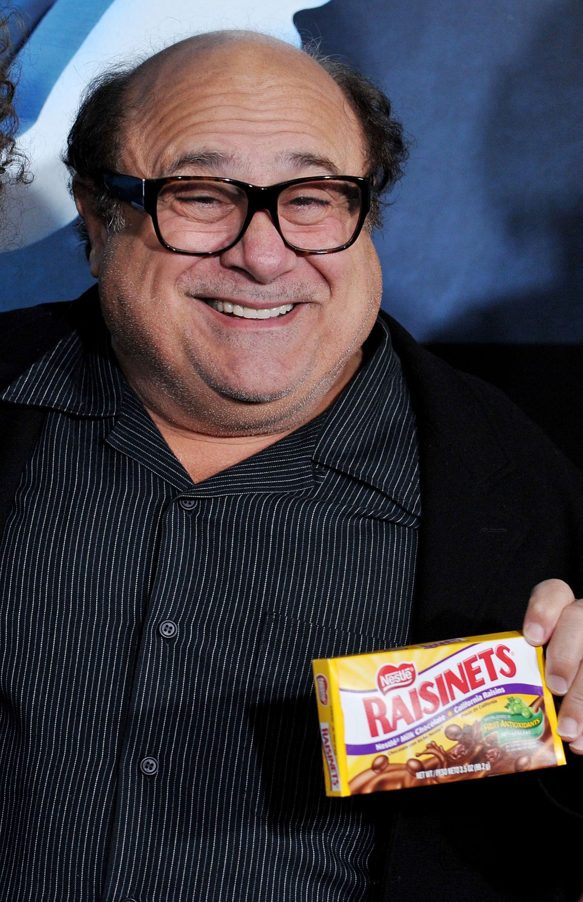 Danny DeVito mostra una scatola di uvetta e sorride