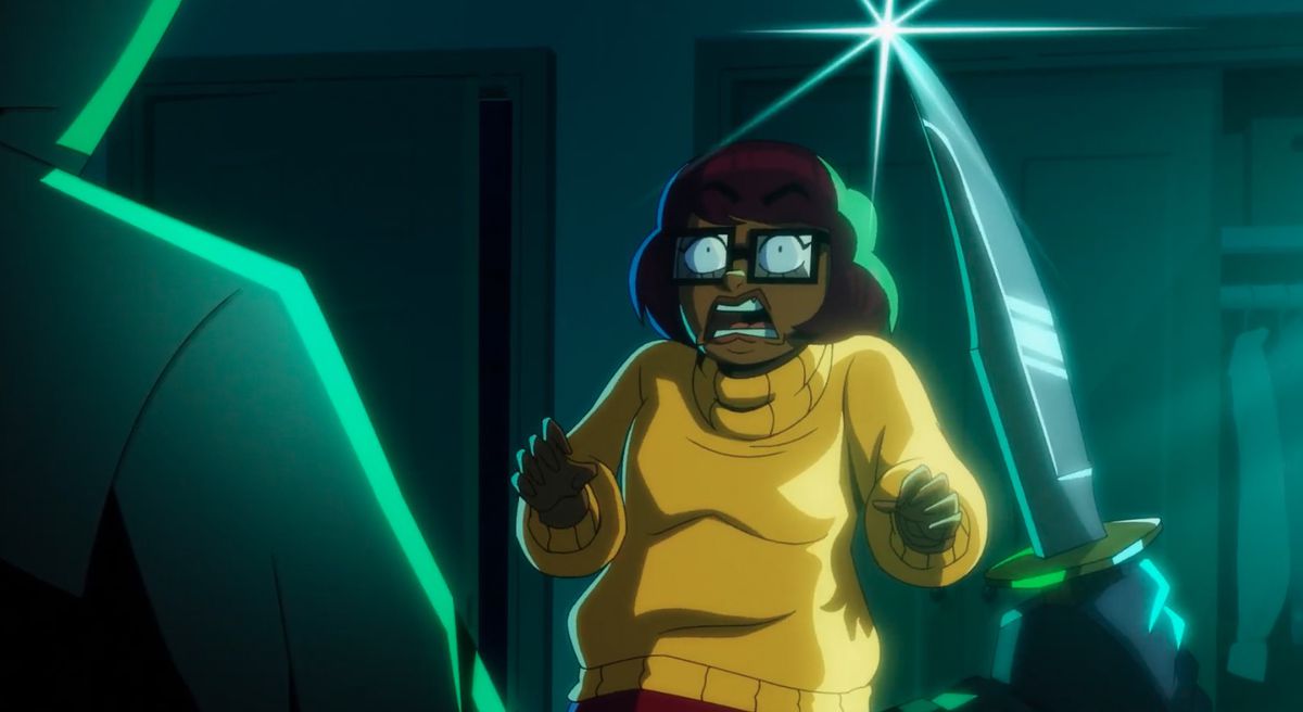Un assassino senza nome che impugna un coltello si insinua su Velma, che urla di terrore, nella serie animata Velma