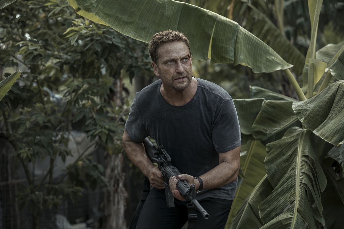 Il Brodie di Gerard Butler, sanguinante dal lato sinistro del viso, corre attraverso la giungla con la sua pistola in Aereo