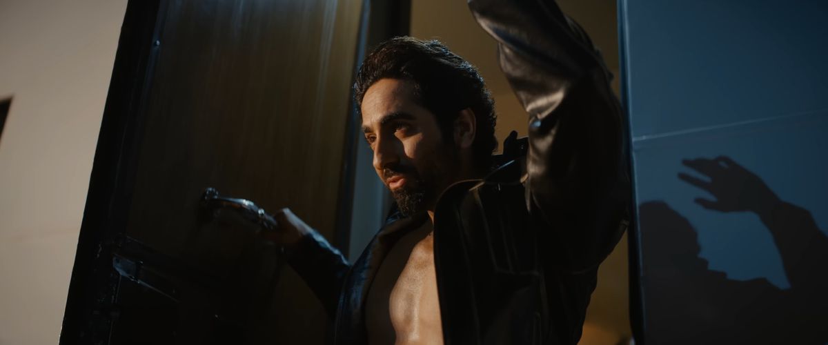 Un bell'uomo saluta la folla da un balcone con la camicia aperta in An Action Hero.