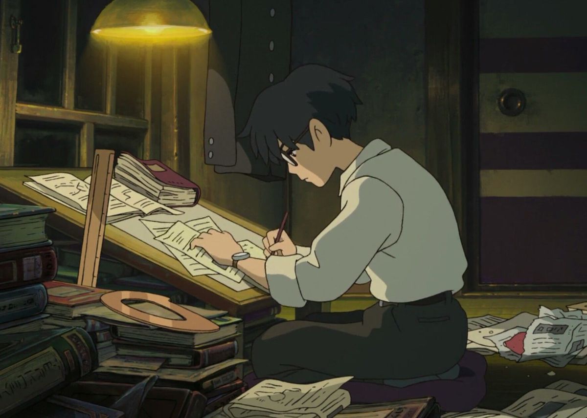 Jiro lavora al suo tavolo da disegno illuminato da una luce sporgente in The Wind Rises