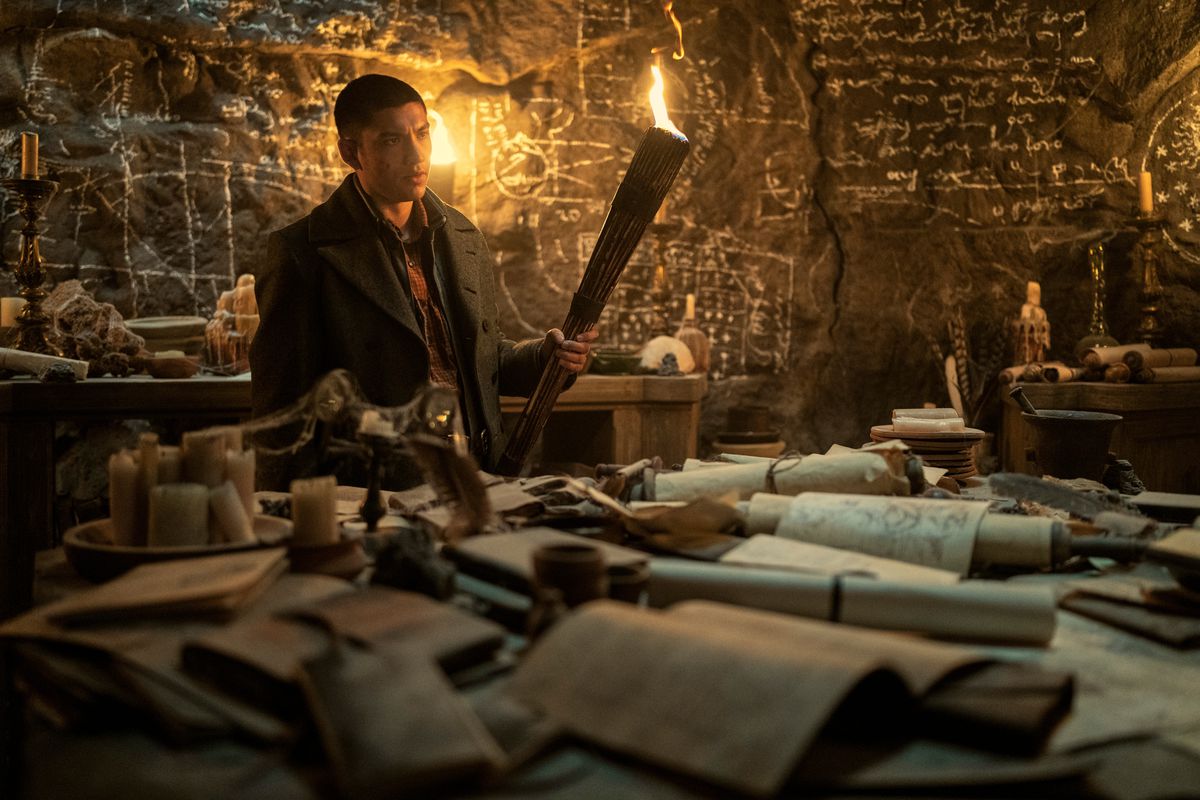 mal seduto davanti a una scrivania cosparsa di mappe. tiene una torcia