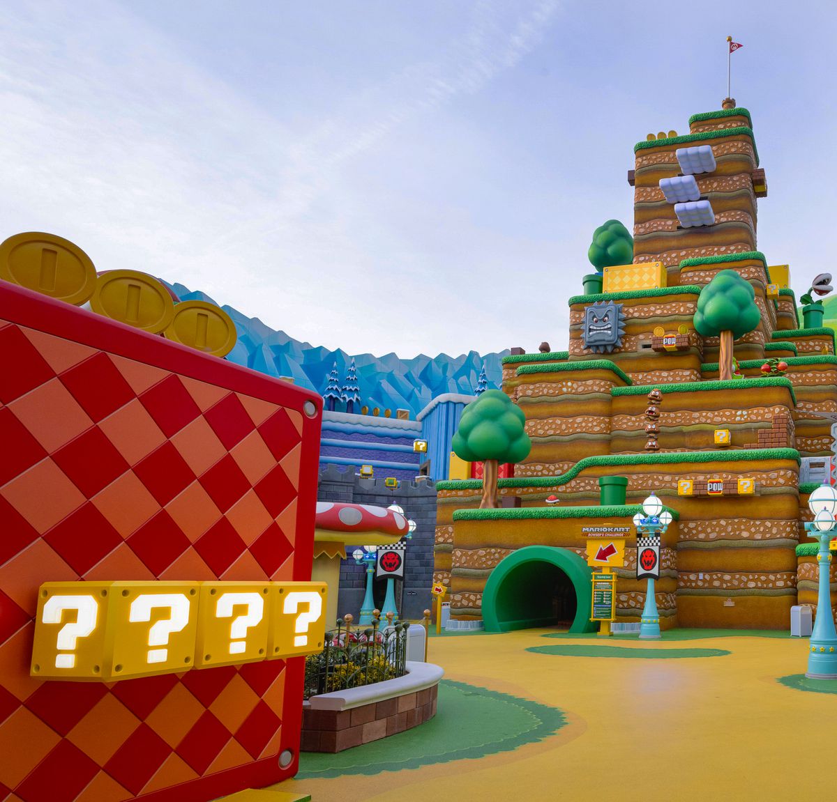 L'ingresso a Mario Kart: La sfida di Bowser al Super Nintendo World negli Universal Studios di Hollywood. Un grande pezzo di scenario emula l'aspetto di un livello di Super Mario Bros., con molti blocchi di monete, blocchi POW e Thwomps punteggiati dappertutto.