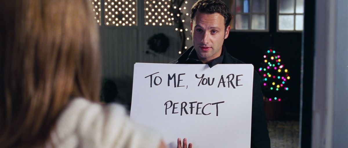 Andrew Lincoln is Love Actually tiene in mano un cartello di carta bianca che dice