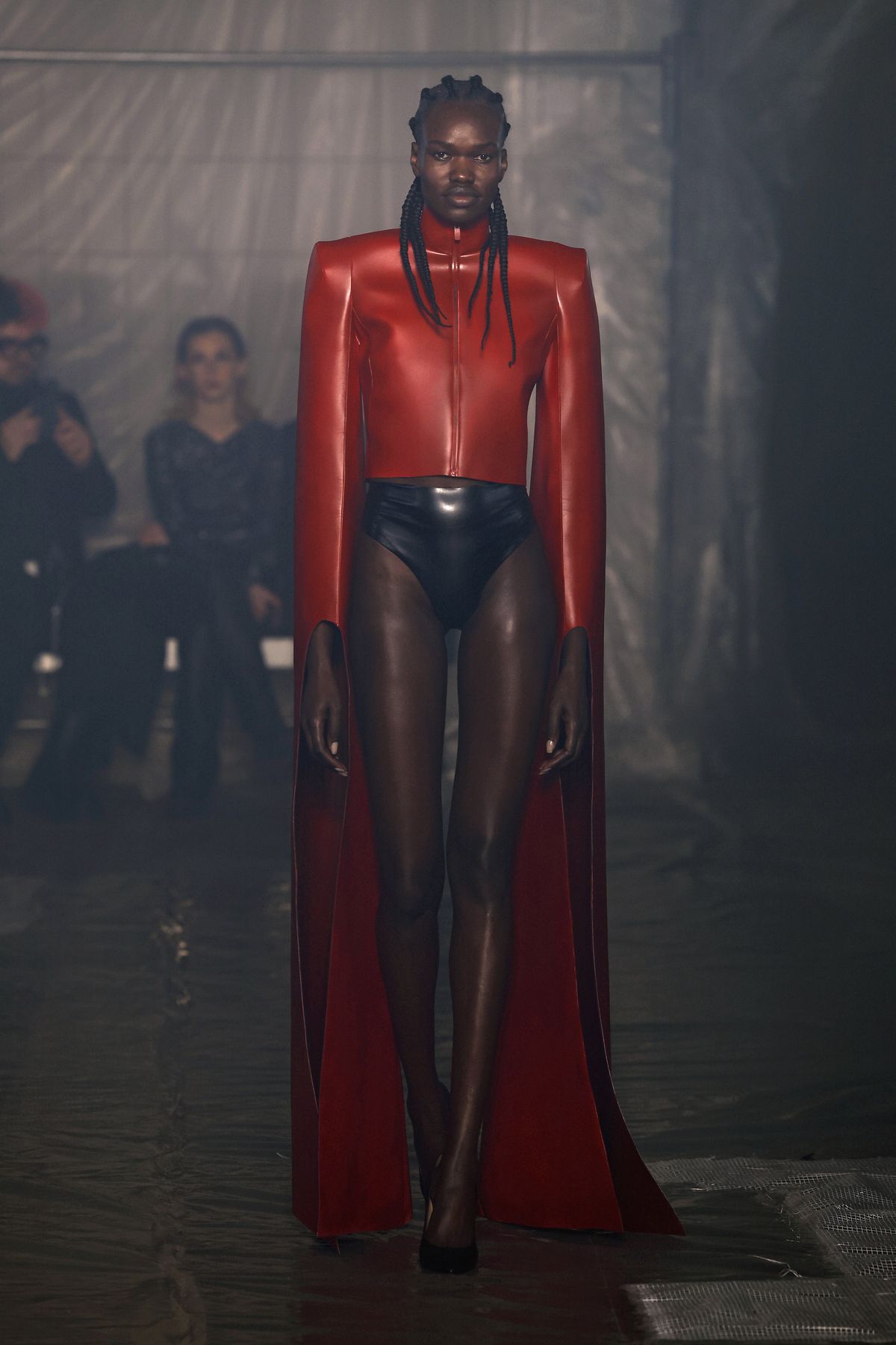 Una modella che indossa una giacca di pelle rosso brillante e slip in pelle cammina sulla passerella della sfilata di Han Kjobenhavn alla settimana della moda di Milano.